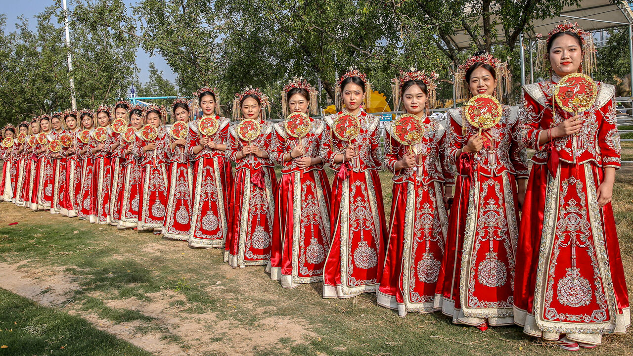Brides in traditional Chinese costumes pose during a group wedding ceremony  in Shanxi, a province in northern China