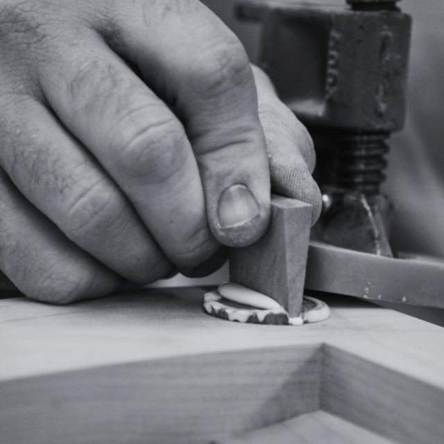 A hand holds a wedged tenon in place.