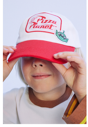 Child wearing red and white Pizza Planet cap from Toy Story collection