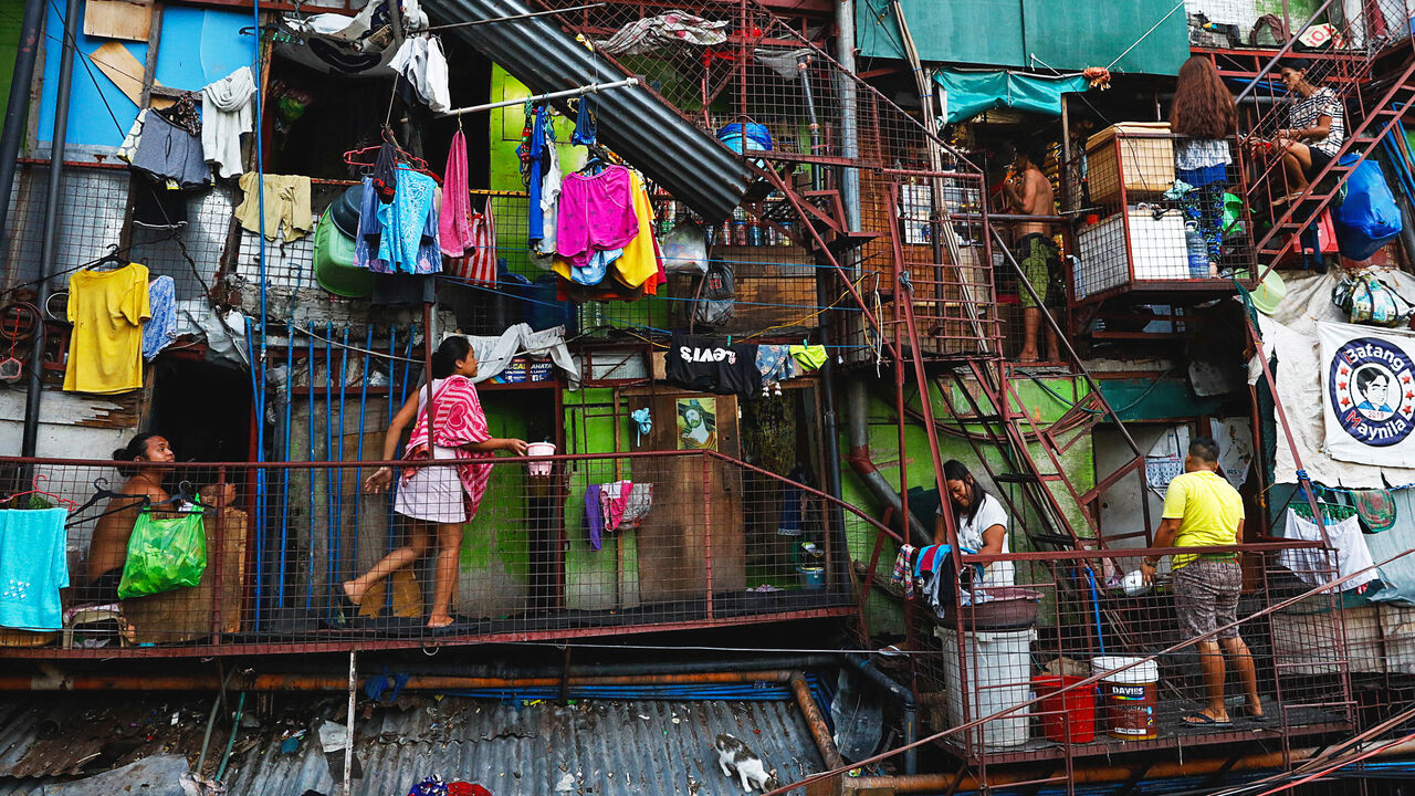Residents of a small apartment building in Manila do household chores outside their units