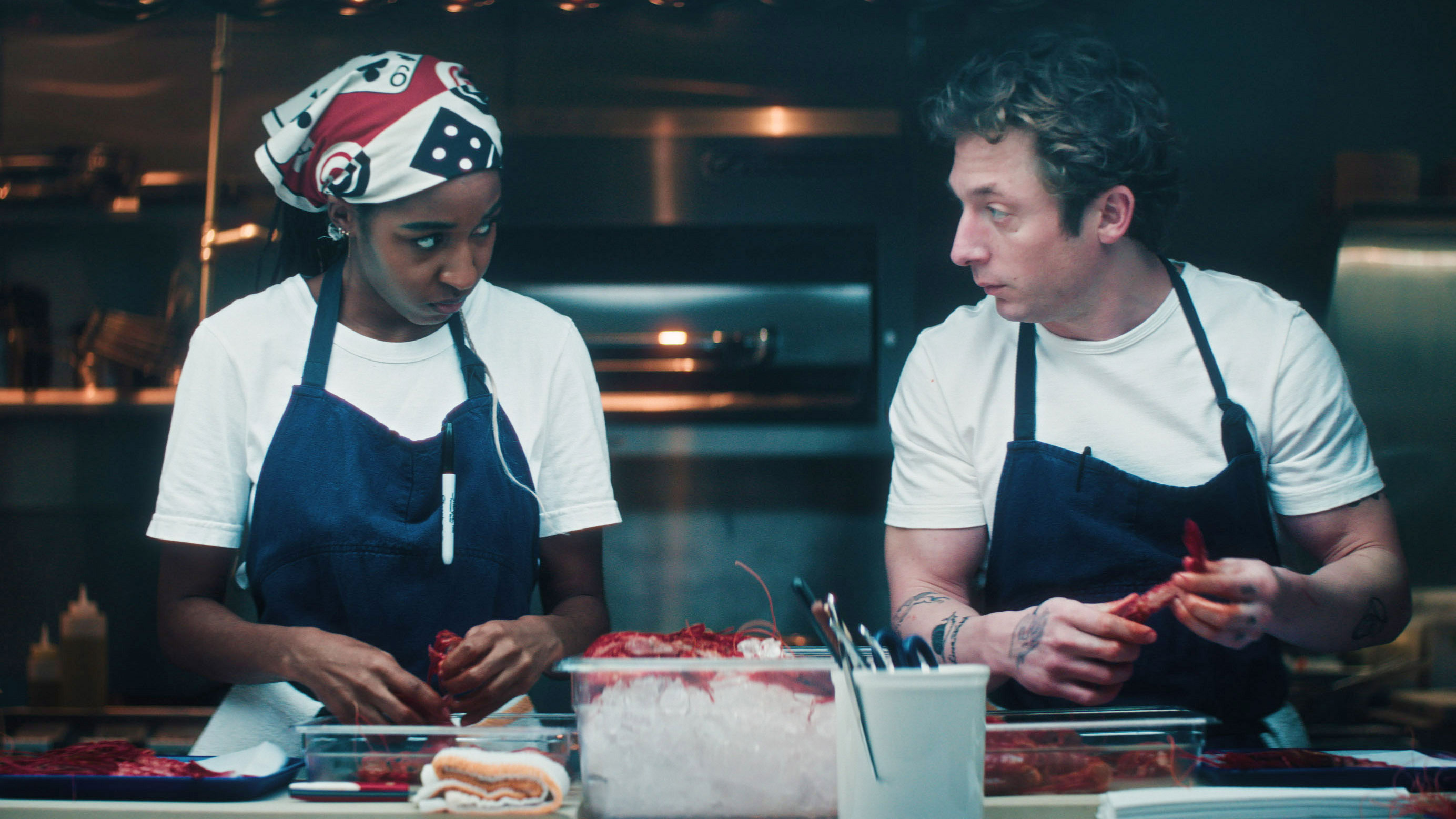 Two people look at each other in a kitchen.
