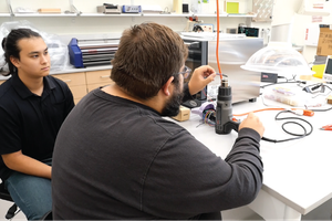 Two people work on a soldering demonstration