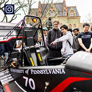 Students point at a Penn Electric Racing car in front of College Hall.