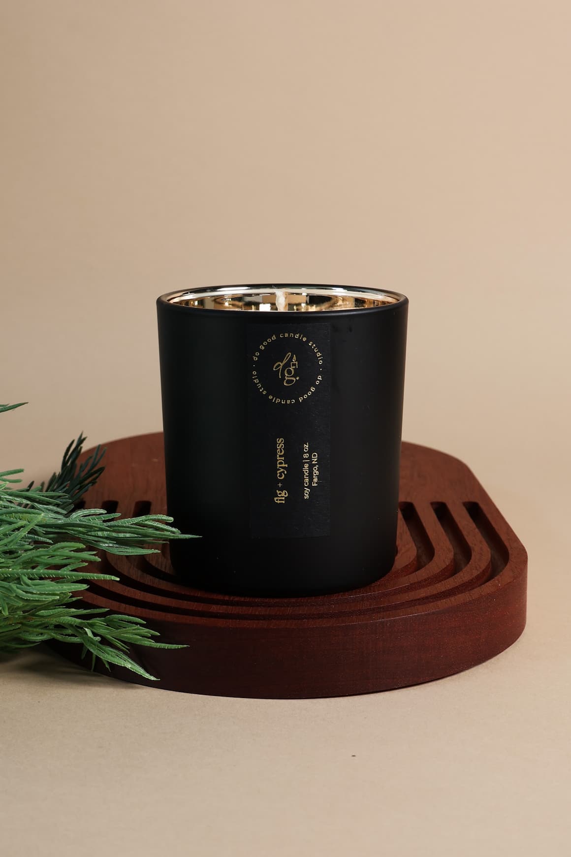 fig + cypress candle styled on a wooden board with an evergreen sprig