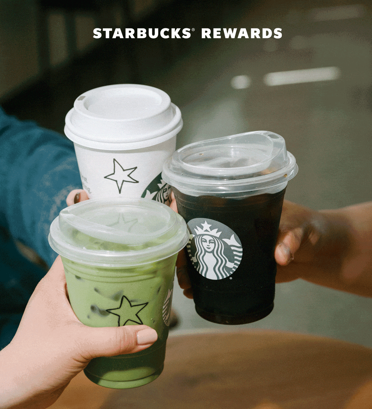 STARBUCKS® REWARDS | Three people cheers their Starbucks drinks together. The cups are decorated with hand-drawn stars."