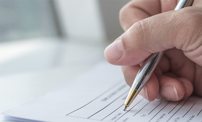 A hand is writing on a form