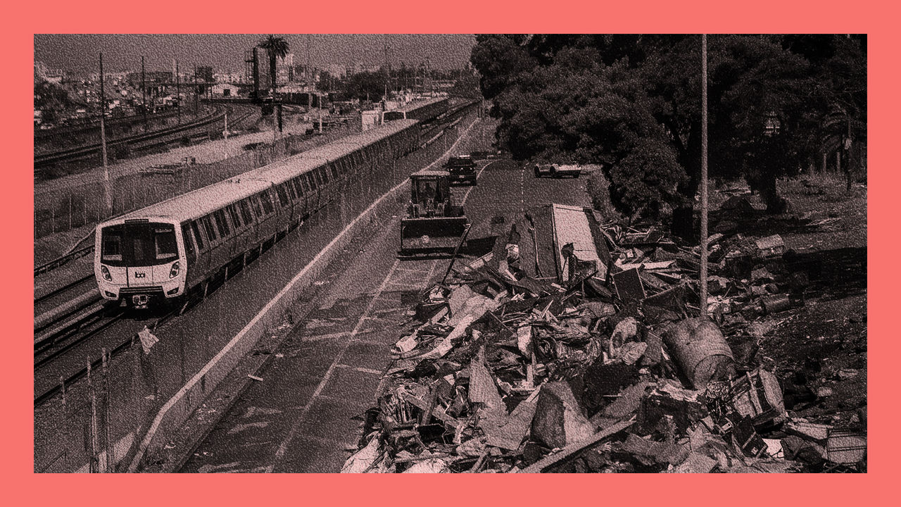 An encampment area is cleaned by a digger next to a train tracks with a train running alongside. Part of  take back the streets from homeless encampments programme in Oakland, California, USA.