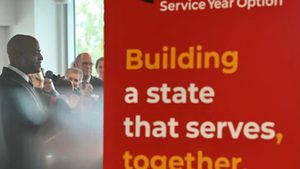 Gov. Wes Moore holds microphone next to red sign that reads, 