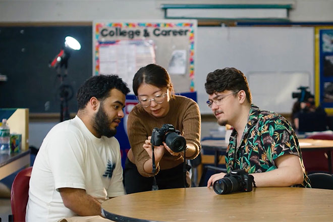 Ejun Mary Hong and Jack Nicholas Roney show a student a camera.