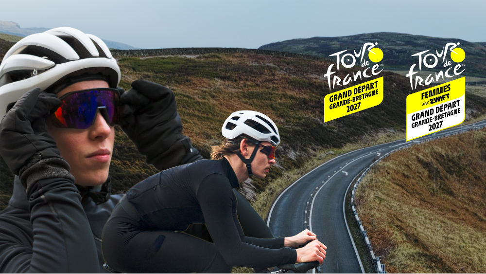 Two road cyclists in dark winter clothing are superimposed onto a sweeping road climb with Tour de France logos in the top right corner.