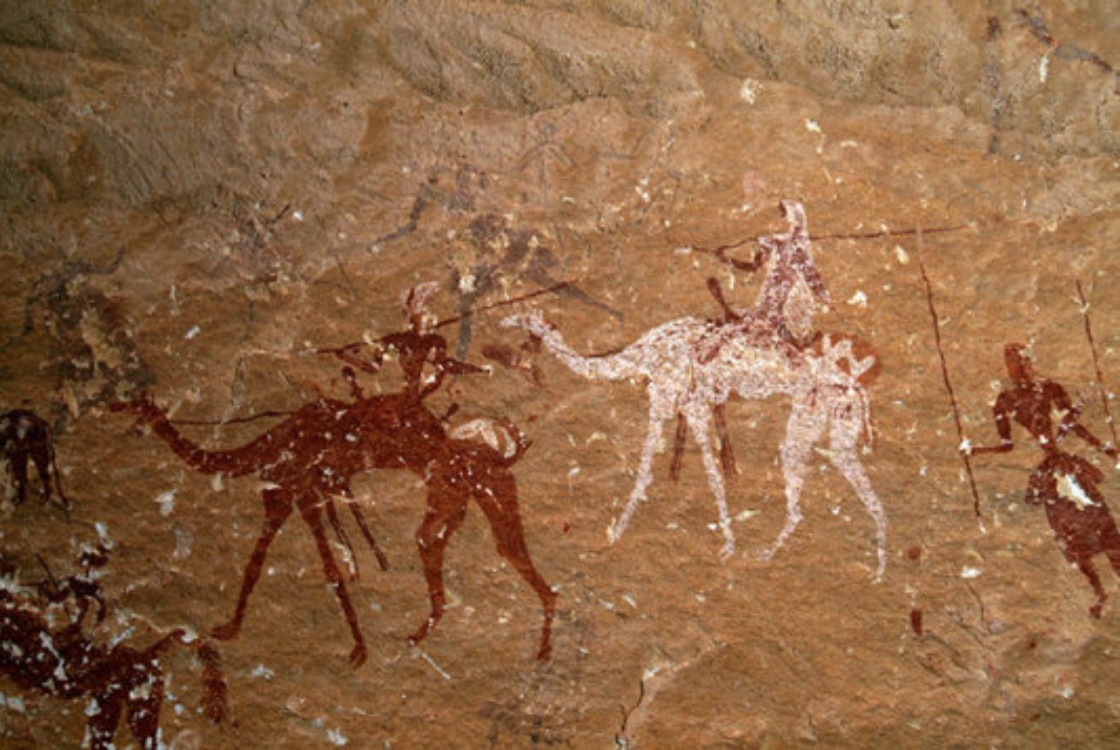 Rock art drawing of people riding camels.