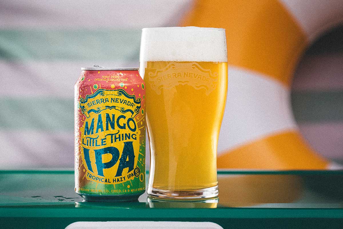 A can and full glass of Mango Little Thing with a pool ring float in the background