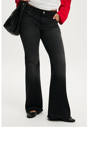 Model wearing black flare jeans with ripped knees and red top with black shoulder bag