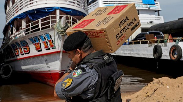 A Military Police officer helps members of the Electoral Justice carry electronic voting machines to a boat for their distribution to indigenous communities along the Rio Negro river, Brazil