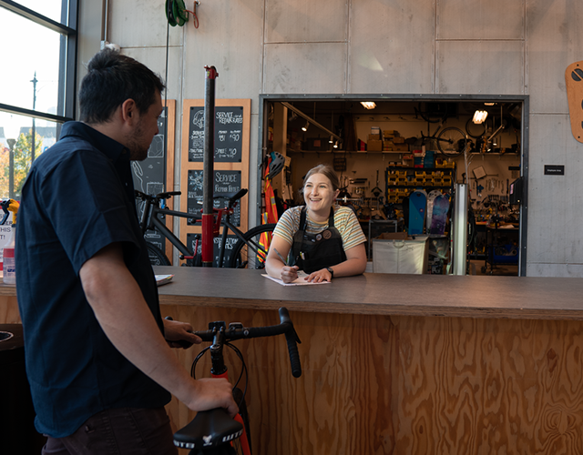 A customer with his bike talking to a bike shop employee at the shop counter