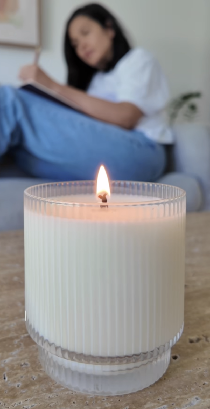 image of candle burning and woman journaling in the background