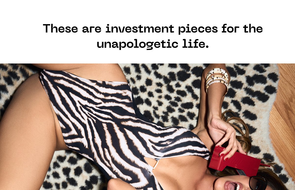 A person in a stylish swimsuit poses on a leopard print rug, holding a red phone.