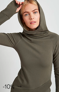 Maritza in The Geneva Sweatshirt with extended cuffs raises one arm near her head.
