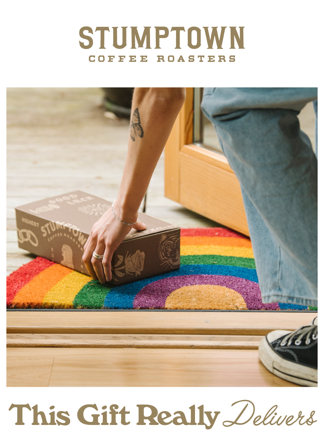 A person picks up a delivered Stumptown Coffee subscription box from a colorful rainbow doormat with the headline, “This Gift Really Delivers.”
