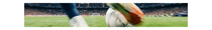 Close up of a soccer player kicking a ball toward goal.