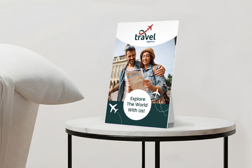 Tabletop promotional sign for a travel agency featuring a couple reading a map and travel icons