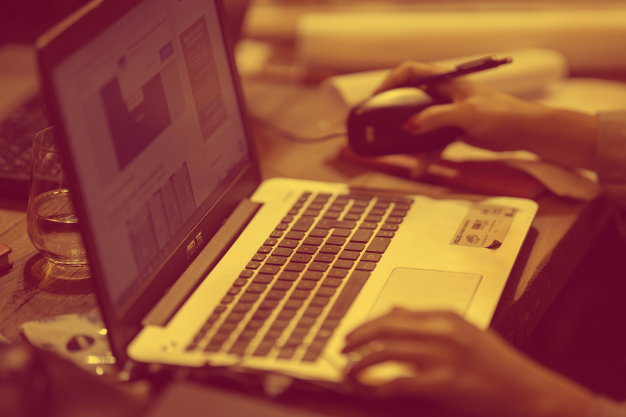 Close up of two arms operating a laptop.