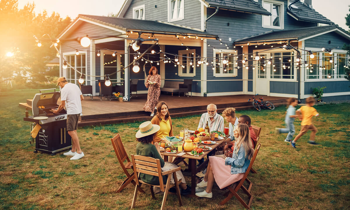 People grilling and dining outdoors in their yard.