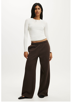 Woman wearing a cream long-sleeve ribbed crop top and brown wide-leg pants