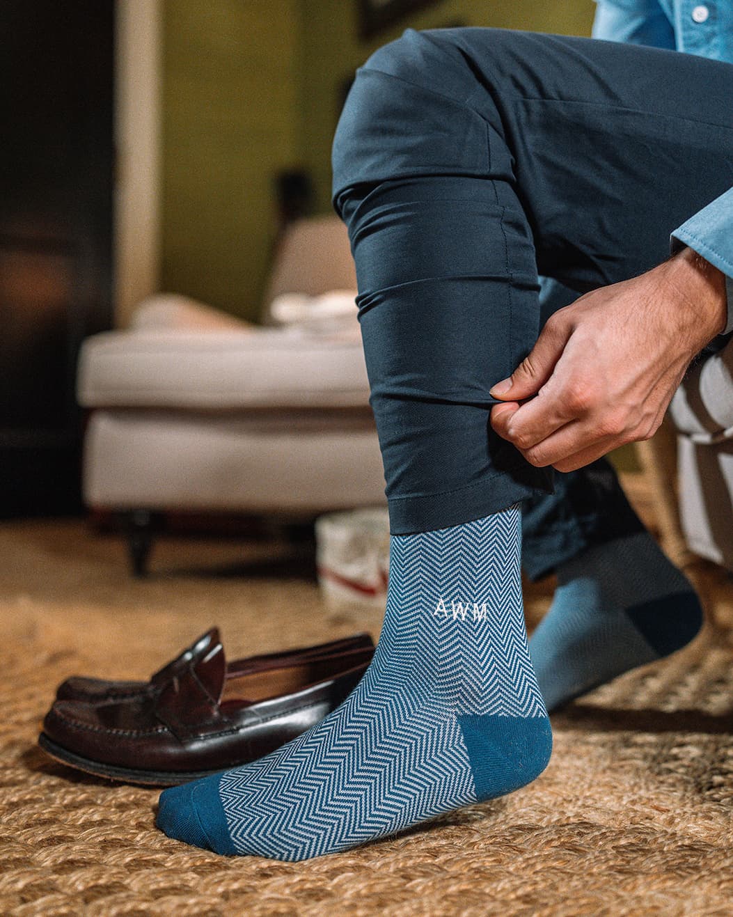 Man walking down stairs with white and grey dress socks with letter MLC monogrammed on