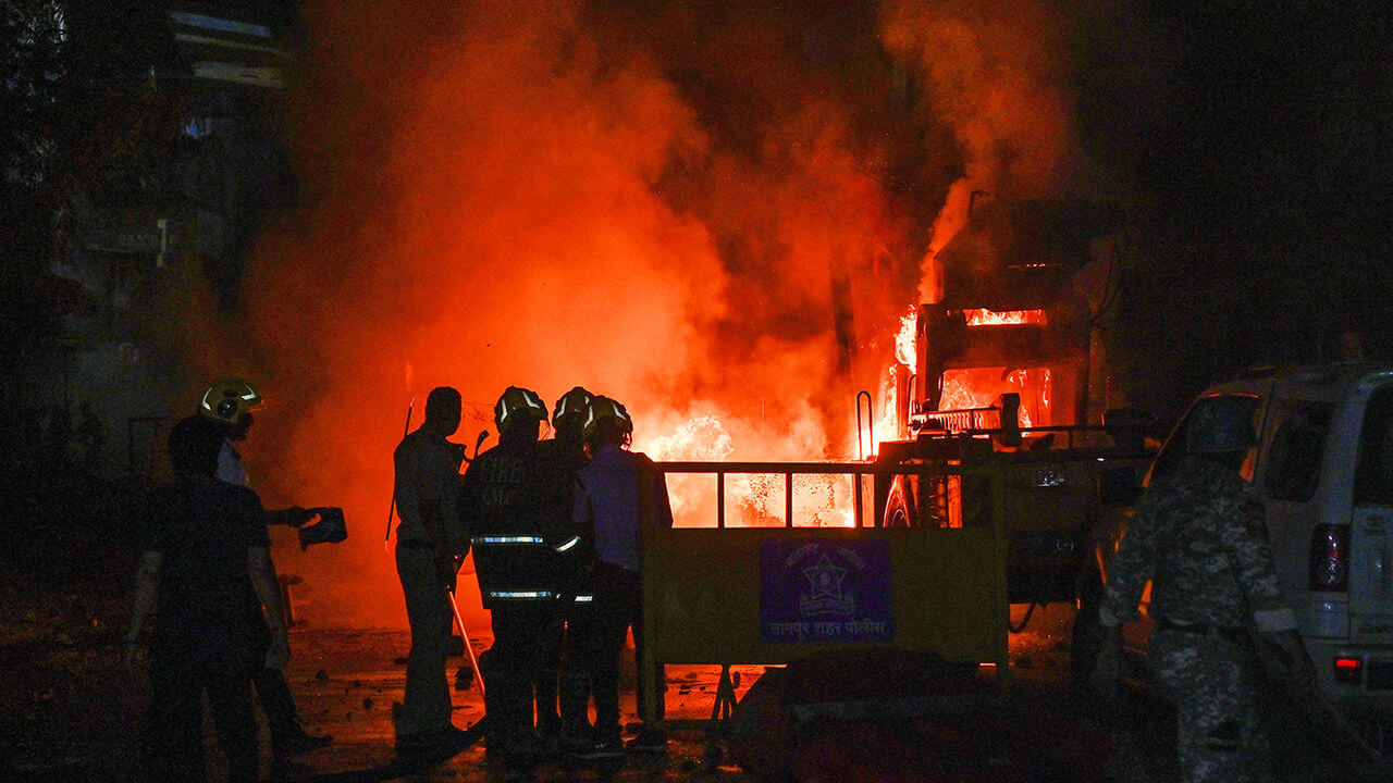 Members of police stand as vehicles burn after clashes erupted due to demands over removal of the tomb of Mughal emperor 