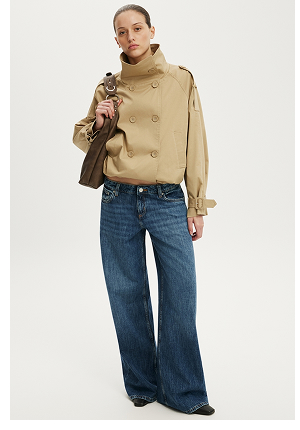 Woman wearing a beige double-breasted cropped jacket with a turtleneck and wide-leg dark blue jeans