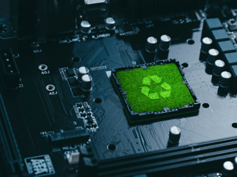A dark shot of a computer motherboard showing the central CPU as a green foliage texture with the triangular recycling logo in the center