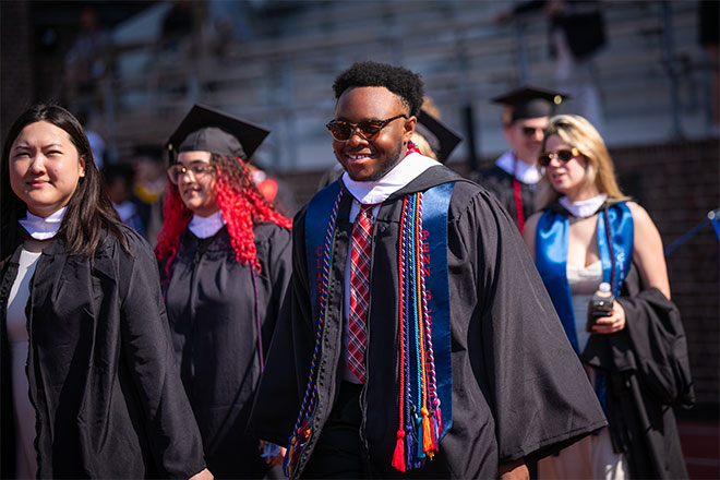 Students walking in graduation robes with multicolored tassels.