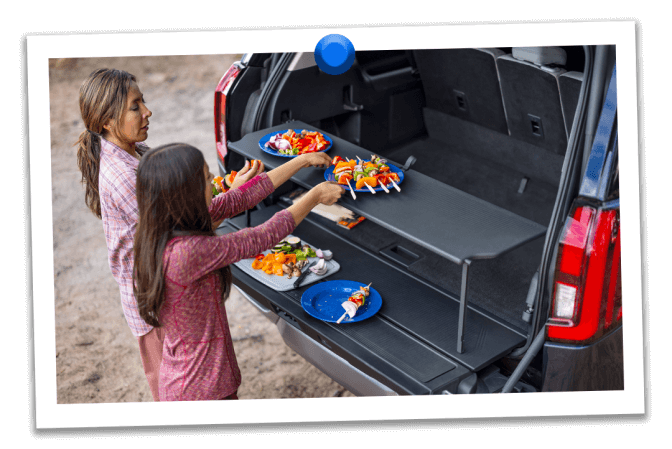 A mother and daughter prepare kebabs at their campsite on the pop‑up tailgate tabletop of their Expedition&reg; SUV 
