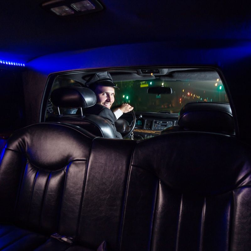 View from the back seat of a limo of the smiling driver looking back through the divider. 
