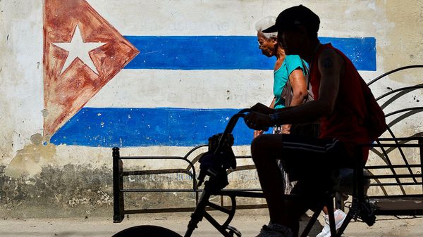 People pass an image of the Cuban flag in central Havana.