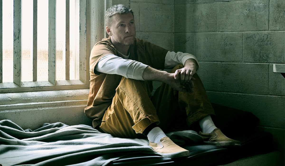 A man sits in a jail cell.