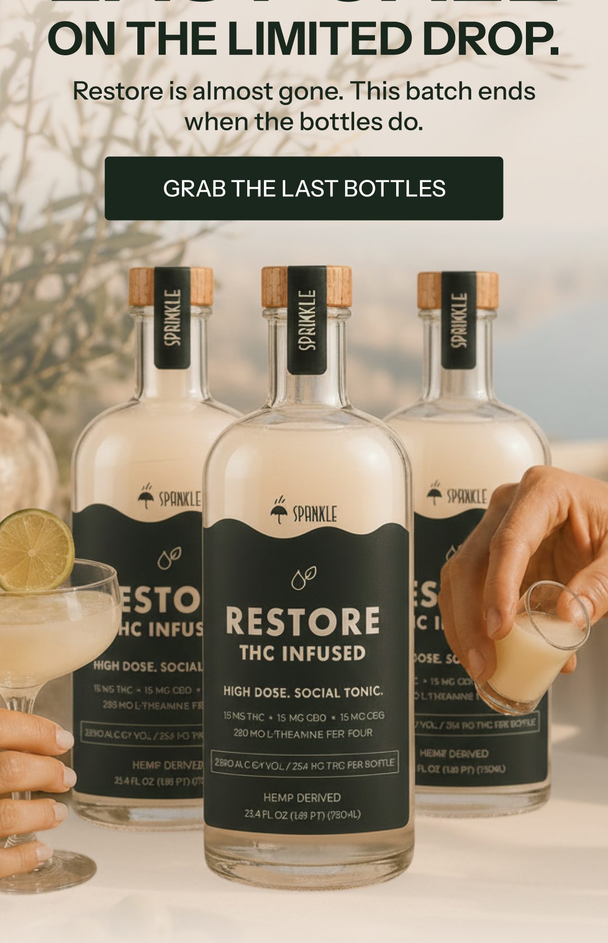 Three bottles of Restore infused tonic with cocktails and limes on a table.