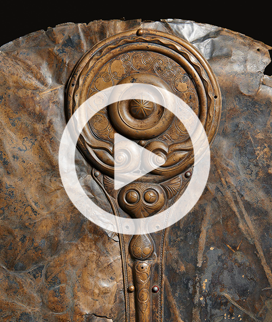 Close up of the Witham shield with a white play button over. 