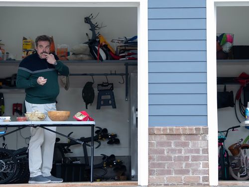 Two figures stand in open garages.