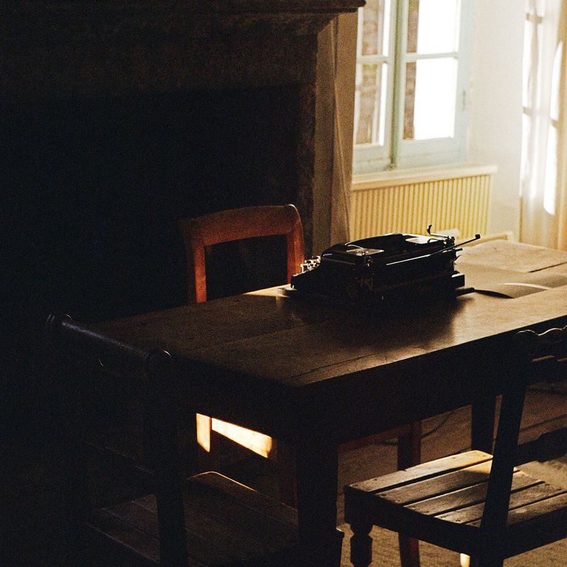 Light falls on a typewriter sitting at an empty table