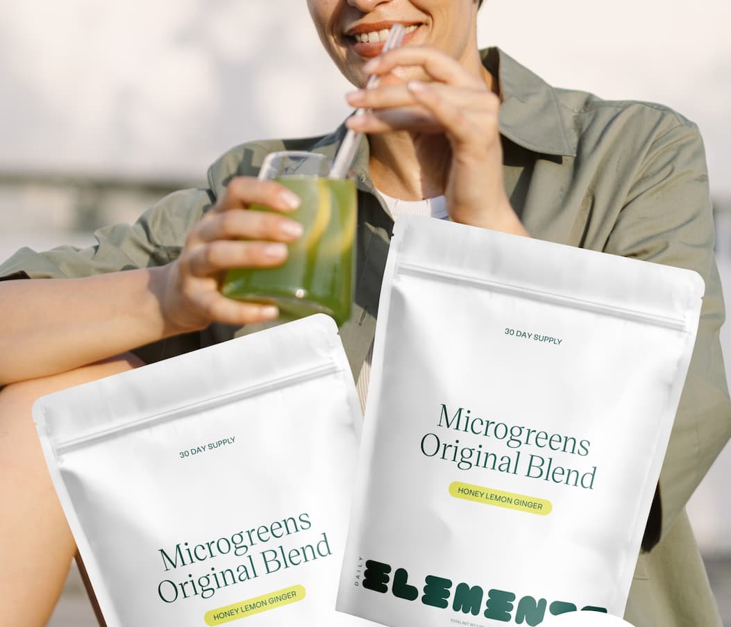 Person drinking a green Daily Elements smoothie with two Honey Lemon Ginger pouches