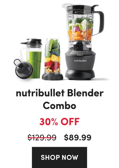 A grey nutribullet Blender Combo filled with chopped vegetables next to personal blending cups with fruit and greens.