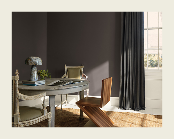 A brown dining room with a circular wood table and three mismatched chairs.