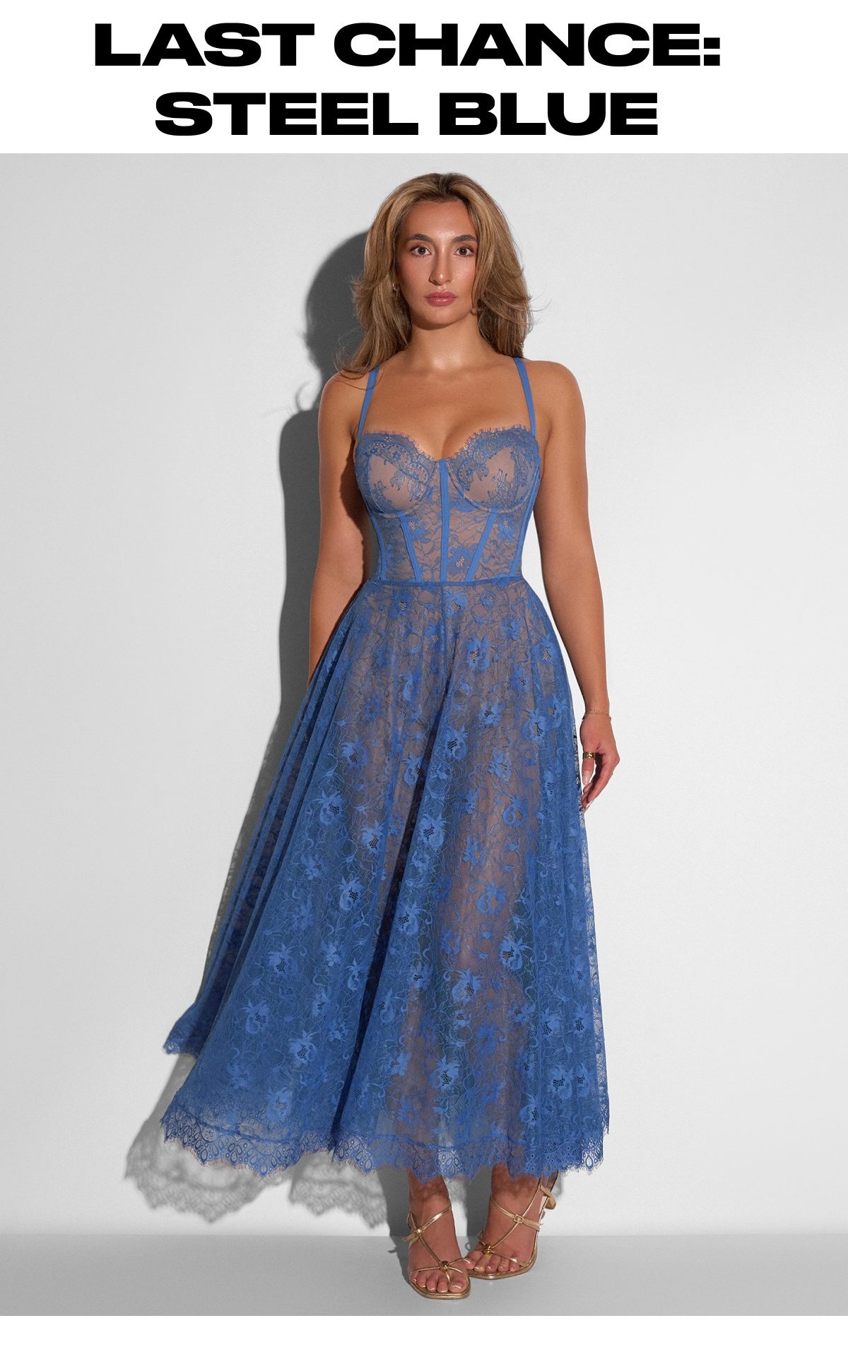 A woman wearing a steel blue lace midi dress with a fitted bodice and a flared skirt.