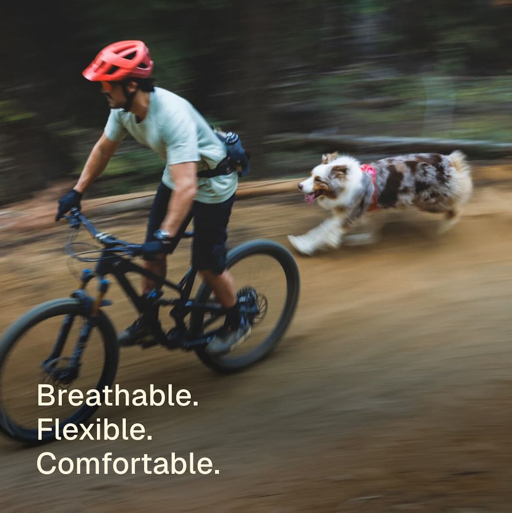 A dog and human race after one another on the trail. Words read: Extra breathability.  Extra flexibility.  Extra comfort.