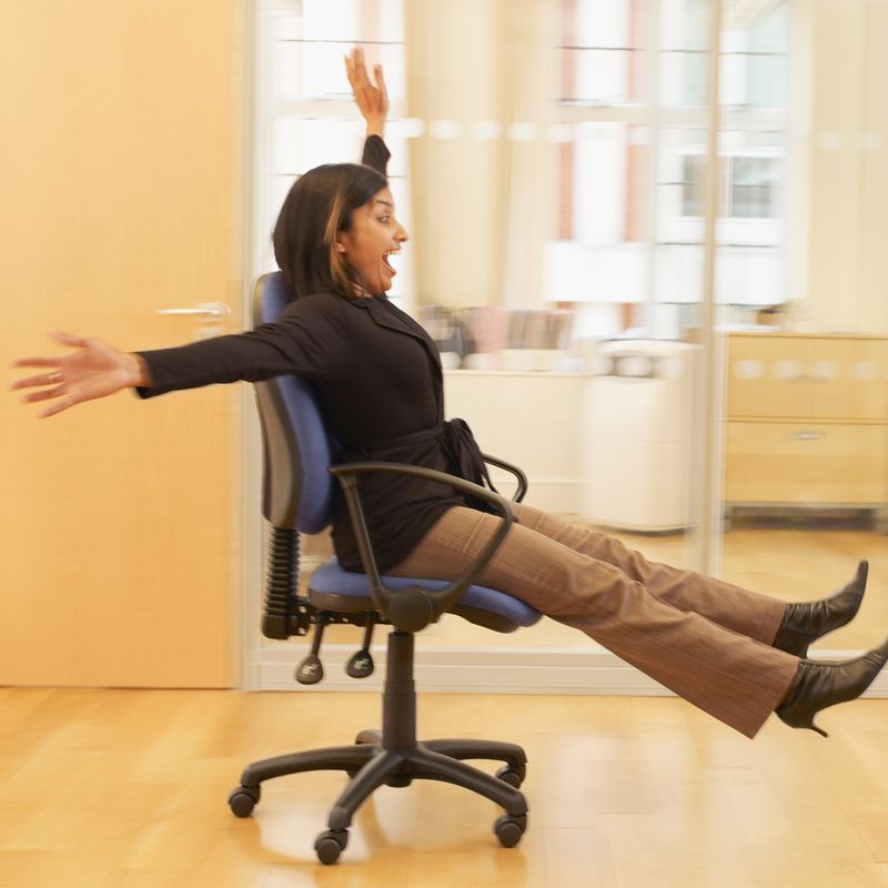 A woman rolling on an office chair.