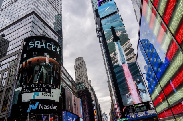 New York's Times Square, with images of Elon Musk and a SpaceX rocket displayed on giant video billboards.