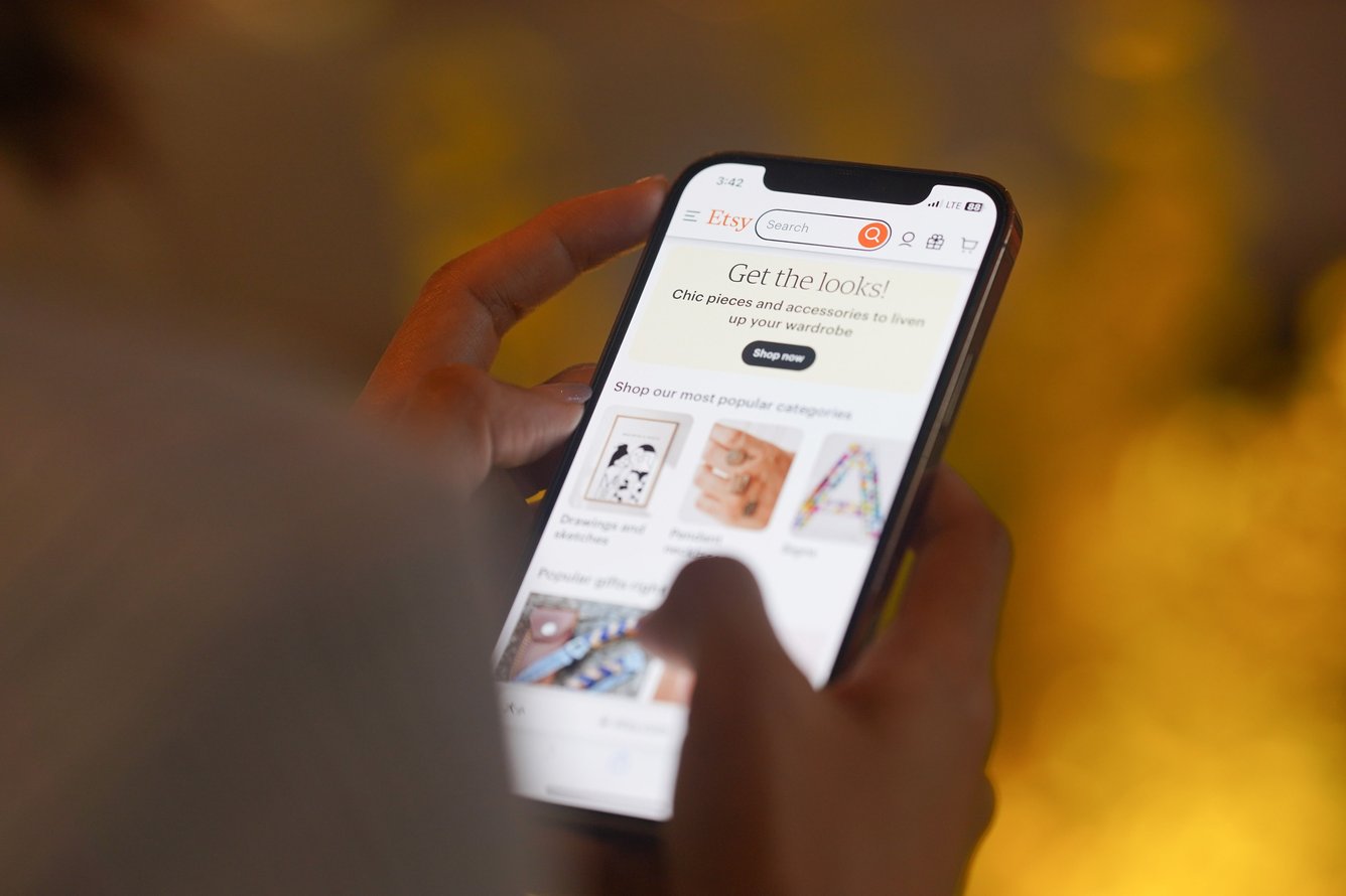 Someone holding a phone and scrolling on Etsy.
