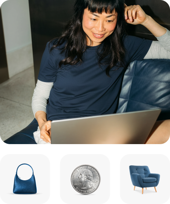 A woman sitting comfortably on a blue couch, smiling while looking at a laptop screen.